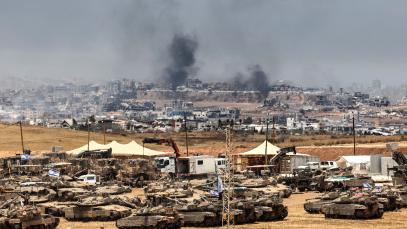This picture taken from a position in southern Israel on the border with the Gaza Strip shows Israeli tanks and bulldozers deployed as smoke billows over destroyed buildings in Gaza during Israeli bombardment on May 17, 2025. 